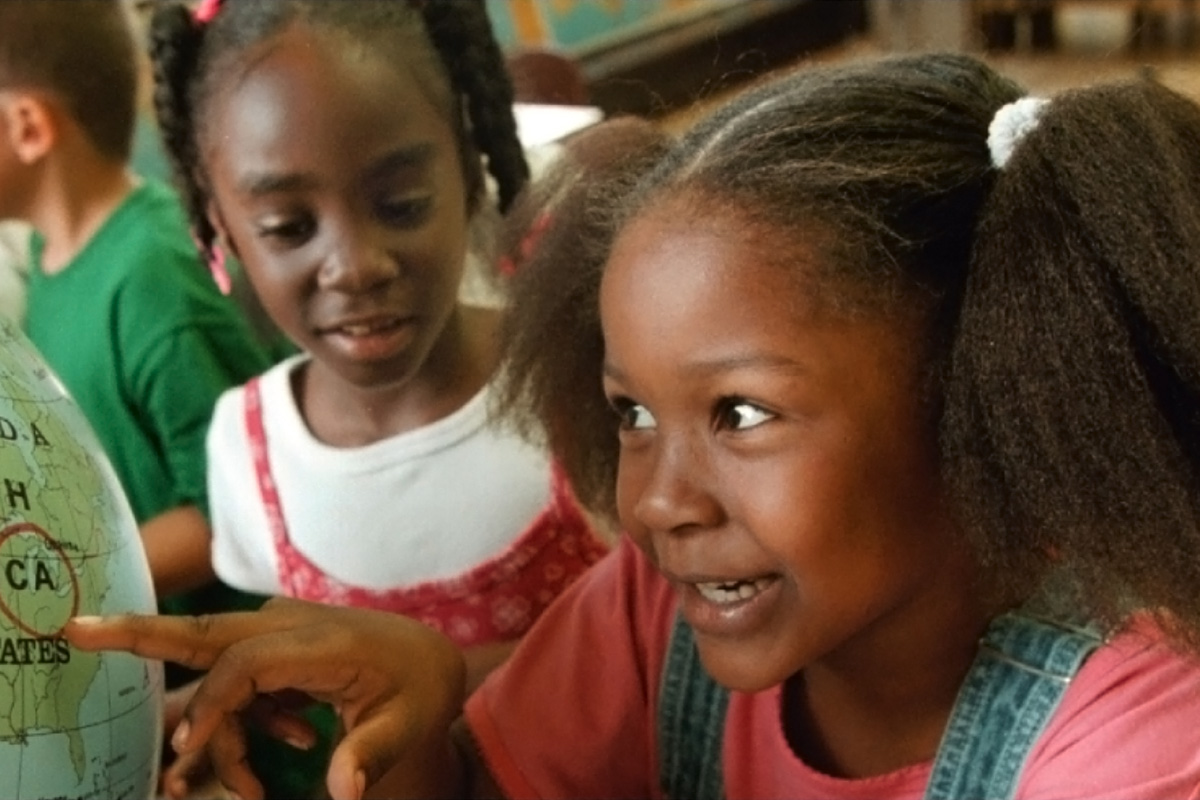 children pointing at a globe